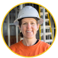 A smiling female electrician wearing an orange T-shirt and white hardhat.