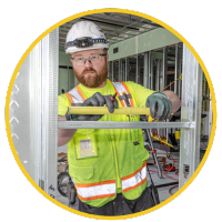 A male construction worker with a red beard wears PPE during an electrical project for commercial construction