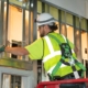 Man in safety gear installing electrical wiring.