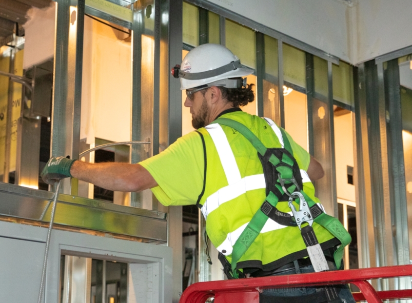 Man in safety gear installing electrical wiring.