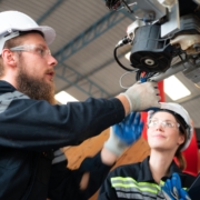 Two electrical technicians work to fix robotics equipment.