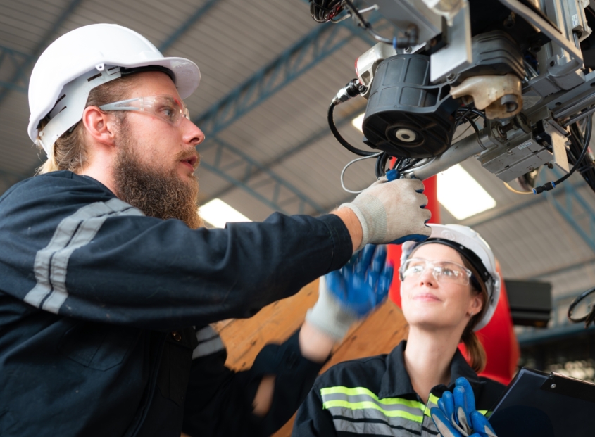 Two electrical technicians work to fix robotics equipment.