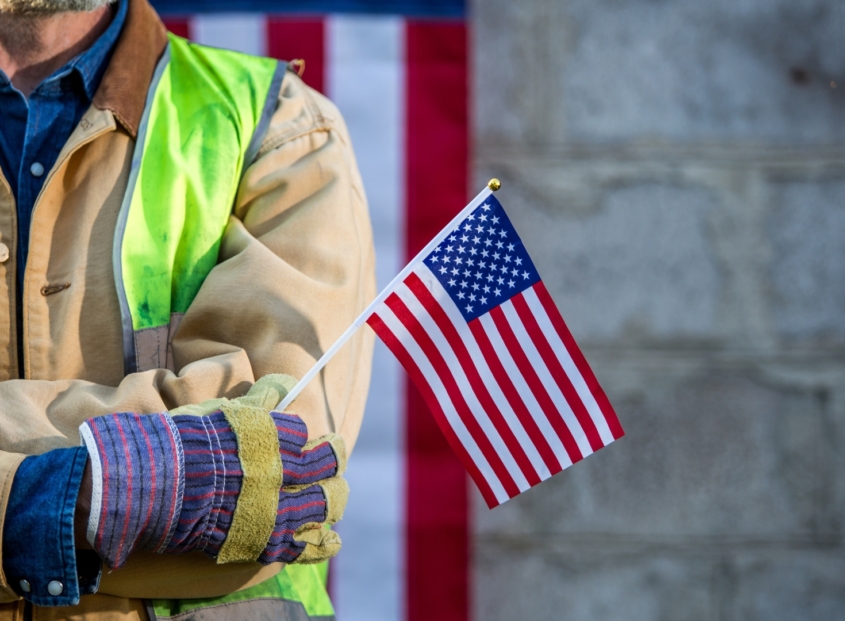 Construction worker holding the American flag.