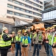 Group of construction workers and commercial electricians stand in front of a building under construction.