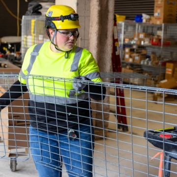 Female IBEW Local 48 union member installing a metal grid for electrical conduit.