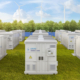 Multiple white energy storage systems (ESS) in a green field with trees in the background.