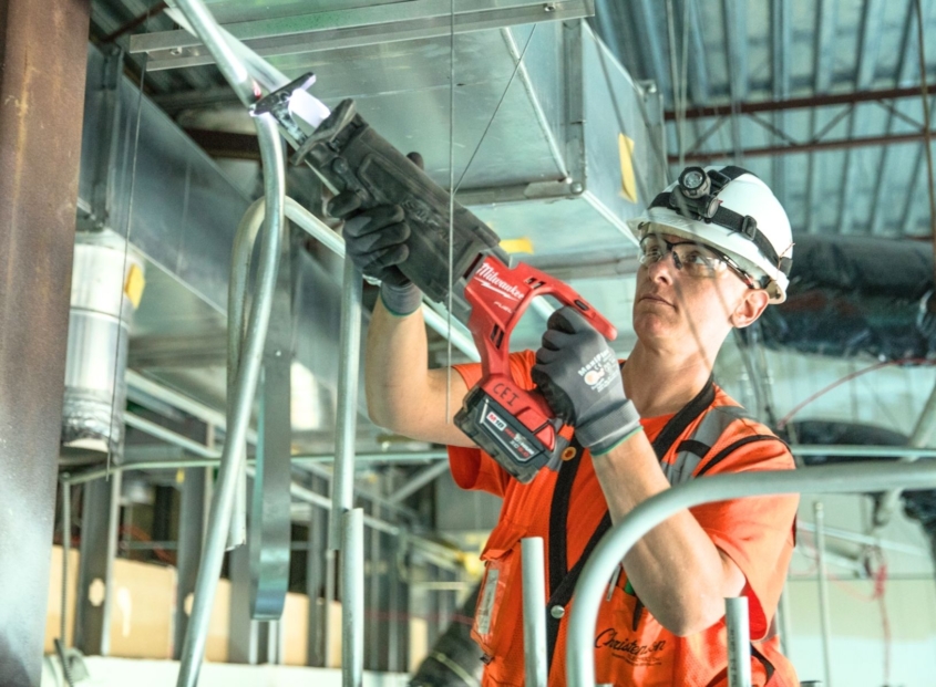 Commercial electrician installs conduit in a large warehouse.