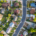 Aerial photo of suburban neighborhood with homes, trees, roads, and cars.