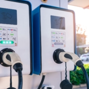 Electric vehicle charging stations with user panels and charging cables in a row.