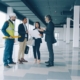Group of four men and women reviewing architectural plans in a newly constructed office building.