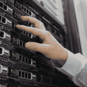 A technician in a white coat installing or adjusting drives in a server rack inside a data center.