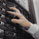 A technician in a white coat installing or adjusting drives in a server rack inside a data center.