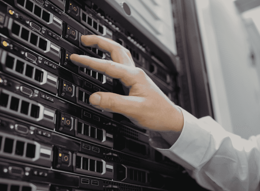 A technician in a white coat installing or adjusting drives in a server rack inside a data center.